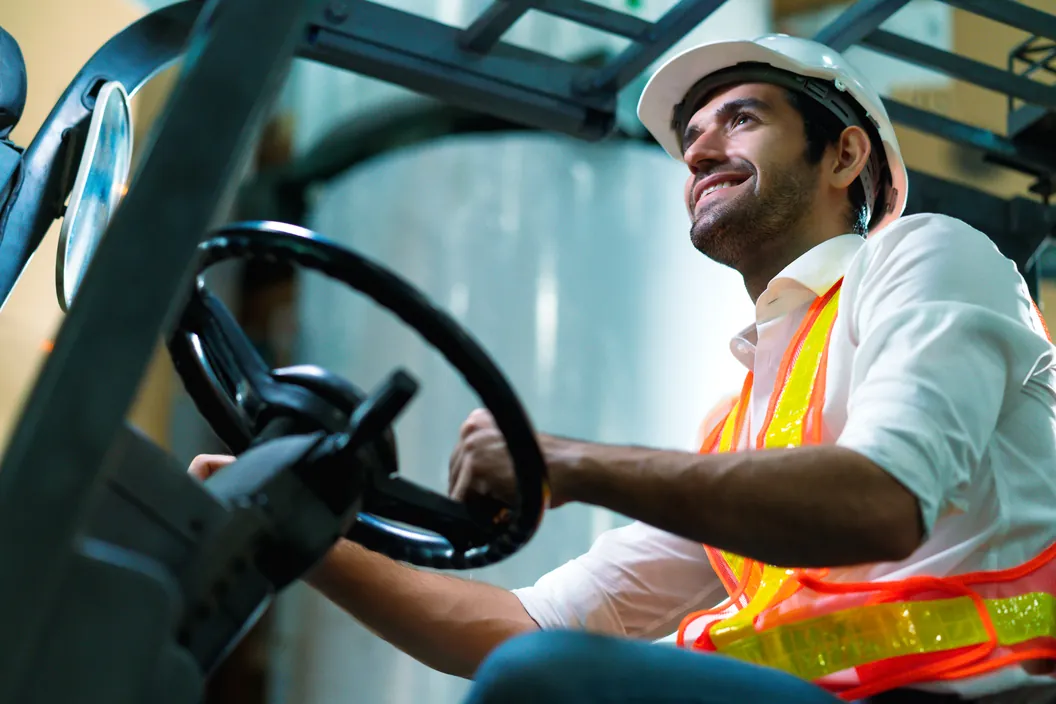 Forklift operator wearing a hard hat and high-visibility safety vest